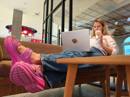 A young woman enjoys coffee while working on her laptopの写真素材