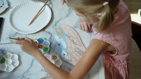 A young mother and her daughter enjoy a creative art session at homeの写真素材