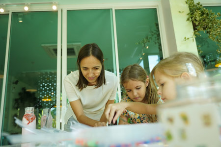 Teacher in workshop teaching two girls how to assemble a mosaic
