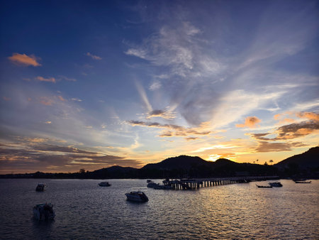 A beautifully serene view of a stunning sunset with fishing boatsの写真素材