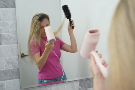 A woman is expertly styling her hair using a blow dryer and brush while in the bathroom