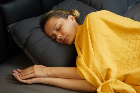 A woman sleeping peacefully under a yellow blanket