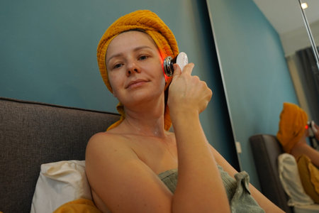 Young woman using infrared massagerの写真素材