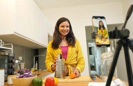 Young woman is broadcasting live from workshop how to prepare a vegetarian foodの写真素材