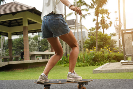 A young woman is skillfully riding a skateboard down a scenic parkの写真素材