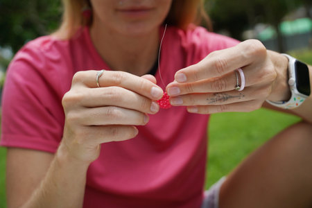 Young woman beading colorful bracelets outdoors in a park