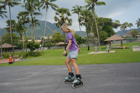 A woman is rollerblading gracefully on a road located in a park