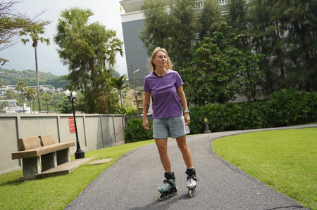 A woman is rollerblading gracefully on a road located in a park