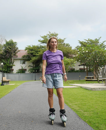 A woman is rollerblading gracefully on a road located in a park