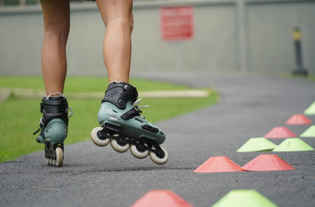 A woman is rollerblading gracefully on a road located in a park