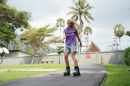 A woman is rollerblading gracefully on a road located in a parkの写真素材