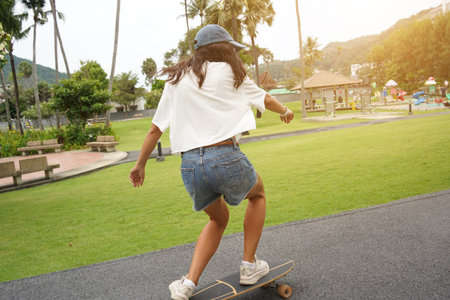 A young woman is skillfully riding a skateboard down a scenic parkの写真素材