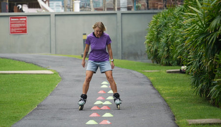 A woman is rollerblading gracefully on a road located in a park