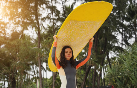 Young woman wearing tight wetsuit is going to surfboard at beautiful beachの写真素材