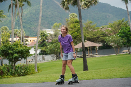 A woman is rollerblading gracefully on a road located in a parkの写真素材