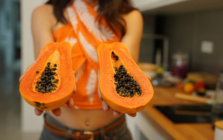 Young woman cuts and peels papaya on the cutting board