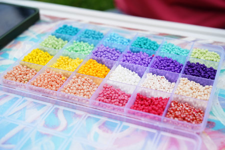 Young woman beading colorful bracelets outdoors in a parkの写真素材