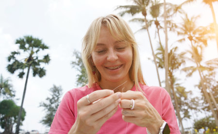 Young woman beading colorful bracelets outdoors in a parkの写真素材
