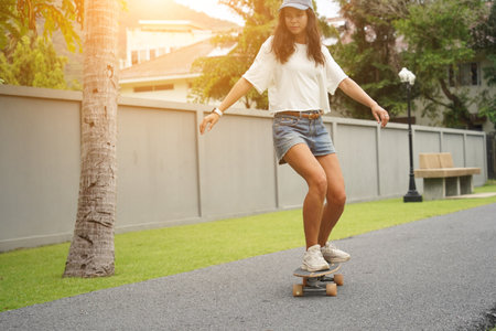 A young woman is skillfully riding a skateboard down a scenic parkの写真素材