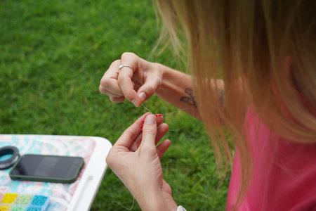 Young woman beading colorful bracelets outdoors in a park