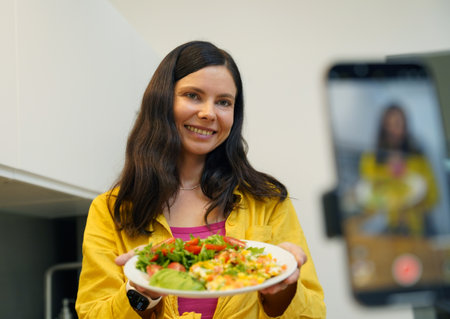 Young woman is broadcasting live from workshop how to prepare a vegetarian foodの写真素材