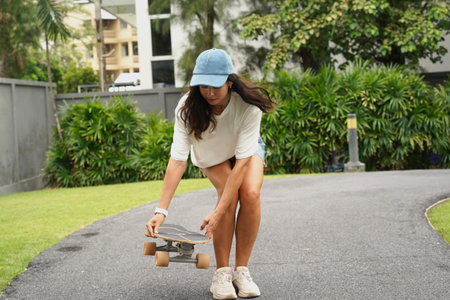 A young woman is skillfully riding a skateboard down a scenic parkの写真素材