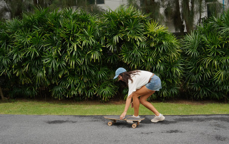 A young woman is skillfully riding a skateboard down a scenic park