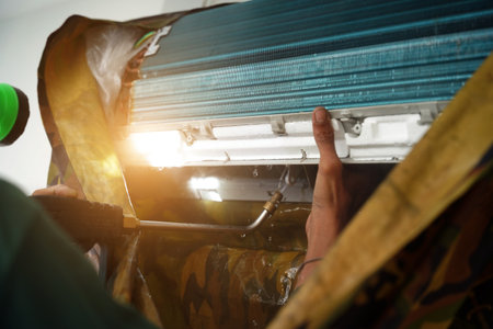 The worker cleans and repairs the air conditioner to ensure it operates properlyの写真素材
