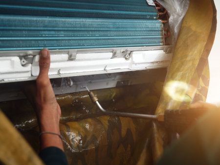 The worker cleans and repairs the air conditioner to ensure it operates properlyの写真素材