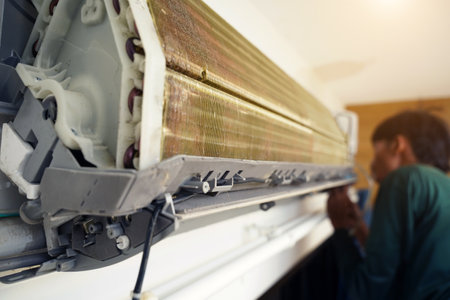 The worker cleans and repairs the air conditioner to ensure it operates properlyの写真素材