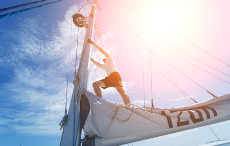 Male captain stands proudly on a sailboat enjoying the momentの写真素材