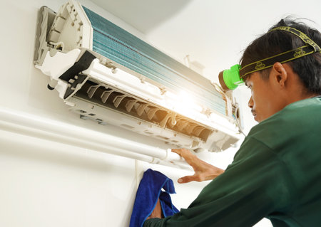 The worker cleans and repairs the air conditioner to ensure it operates properlyの写真素材