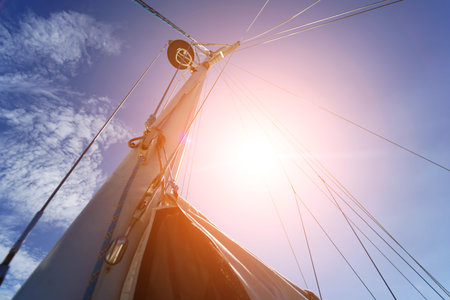 Tall sturdy mast of a sailboat stands out vividly against the bright blue sky.