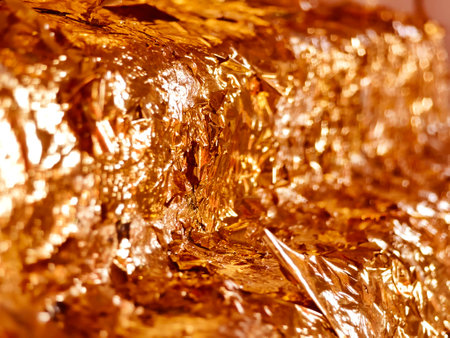 A detailed close up image of a shiny piece of gold foil on a tableの写真素材