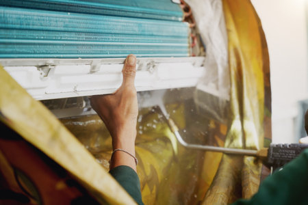 The worker cleans and repairs the air conditioner to ensure it operates properlyの写真素材