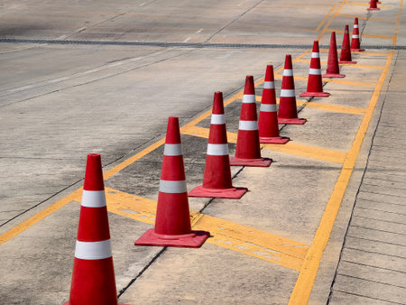 A row of red and white traffic cones is placed by a road