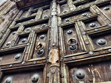 Detailed closeup of an antique wooden door decorated with elegant metal rings mounted on it.の写真素材