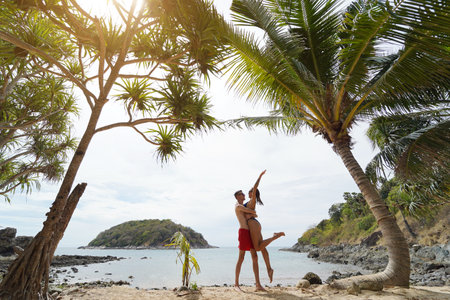 A young couple enjoy a beautiful day on a beach surrounded by tall palm treesの写真素材