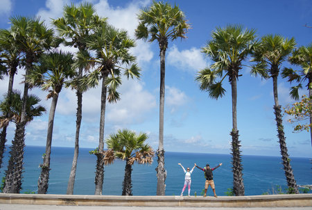 A young couple are standing together in front of majestic palm treesの写真素材