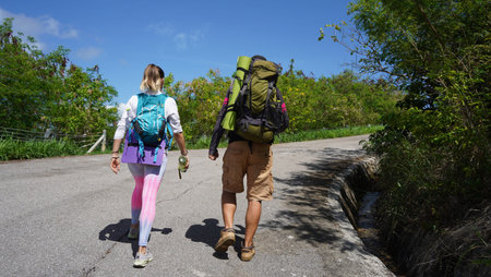 A man and a woman are leisurely walking down a road surrounded by natures beauty and tranquility