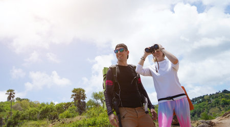 A man and a woman are intently looking through binoculars at something interesting in the distanceの写真素材