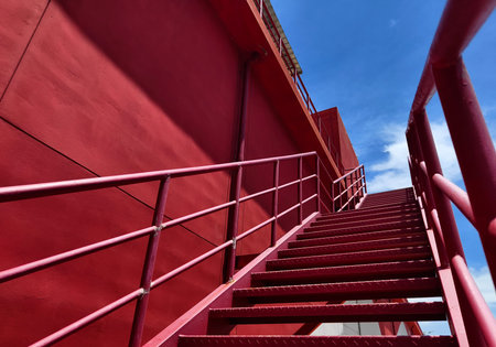A set of stairs ascending a large red wall