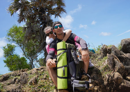 A young couple are hiking on a rugged rocky cliff that offers a view of the ocean
