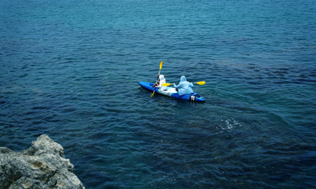 The young couple are happily navigating together in a light blue kayak with yellow paddles