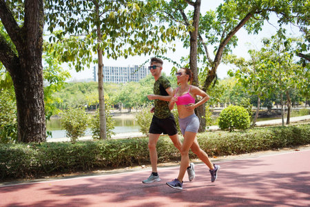 A man and a woman are jogging together in a beautiful parkの写真素材