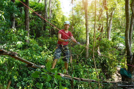 A man is walking across a challenging ropes course in the extreme park