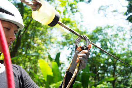 Woman is enjoying an exhilarating ride on a zip line that traverses the thick woods surrounding herの写真素材