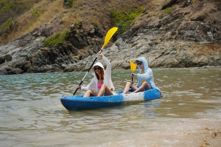 The young couple are happily navigating together in a light blue kayak with yellow paddlesの写真素材