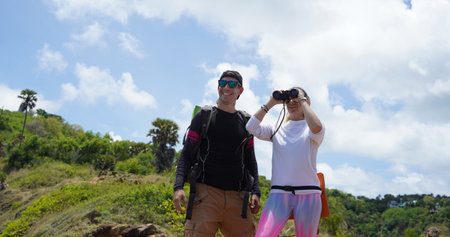 A man and a woman are intently looking through binoculars at something interesting in the distanceの写真素材