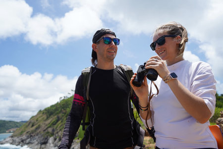 A man and a woman are intently looking through binoculars at something interesting in the distanceの写真素材